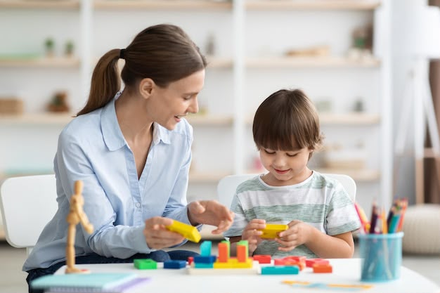 Specialist playing with colourful blocks with a young boy during child development and psychology sessions at MOM's Speech & Hearing Clinic, Vijayawada